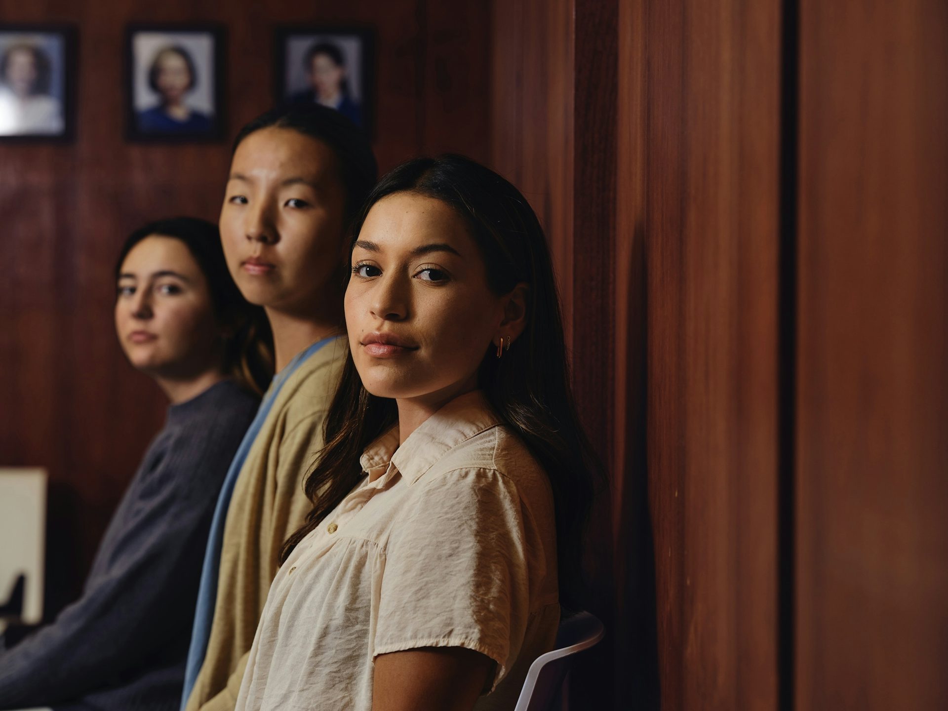 Tres muchachas sentadas en un auditorio